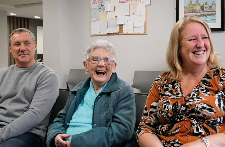 A smiling SpaMedica patient sat between her happy family members in the SpaMedica waiting room