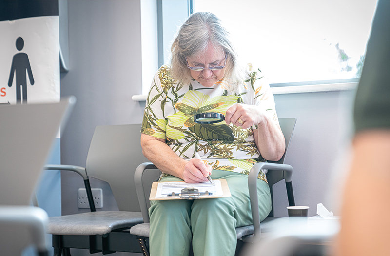 A SpaMedica patient using a magnifying glass to read and complete a form