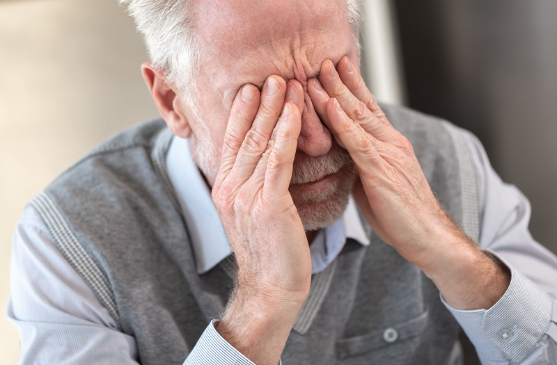 An elderly gentleman rubbing his sore eyes with both hands