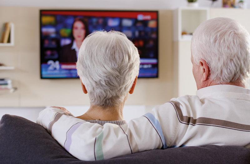 Elderly couple sat on the sofa watching television