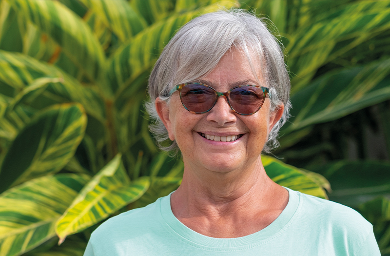 A happy elderly woman smiling whilst wearing her sunglasses