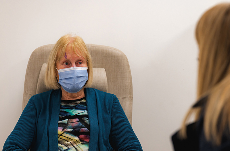 A SpaMedica patient wearing a face mask and talking to someone