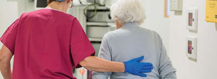 Happy SpaMedica nurse walking and chatting with patient post surgery