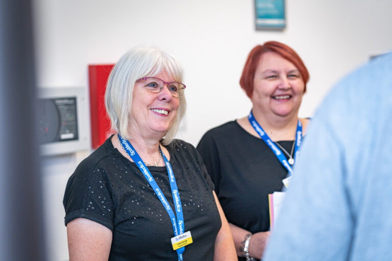 Two smiling SpaMedica employees talking to a SpaMedica patient