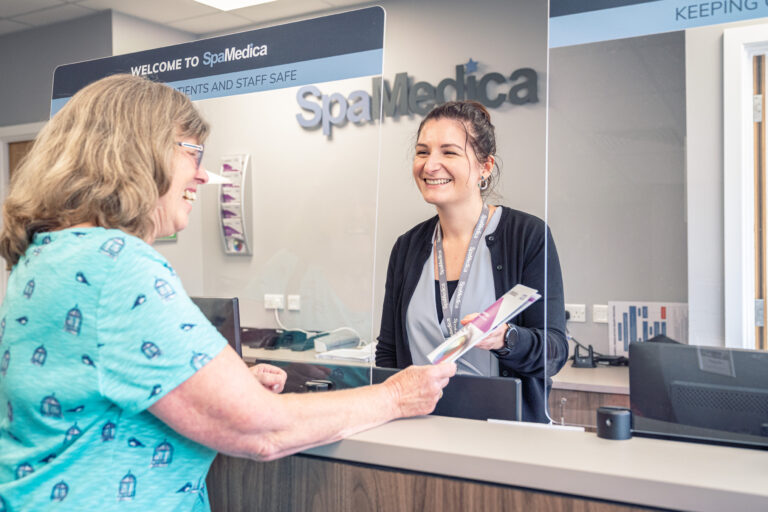 Happy SpaMedica patient coordinator discussing brochure with delighted patient