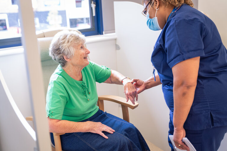 SpaMedica nurse checking the details on the wristband of a SpaMedica patient sat in a chair