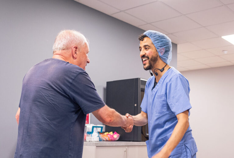 A SpaMedica consultant surgeon smiling and shaking the hand of a SpaMedica patient, following a successful cataract surgery
