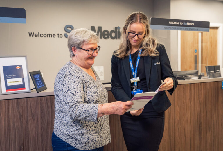 SpaMedica employee handing a brochure to a happy SpaMedica patient