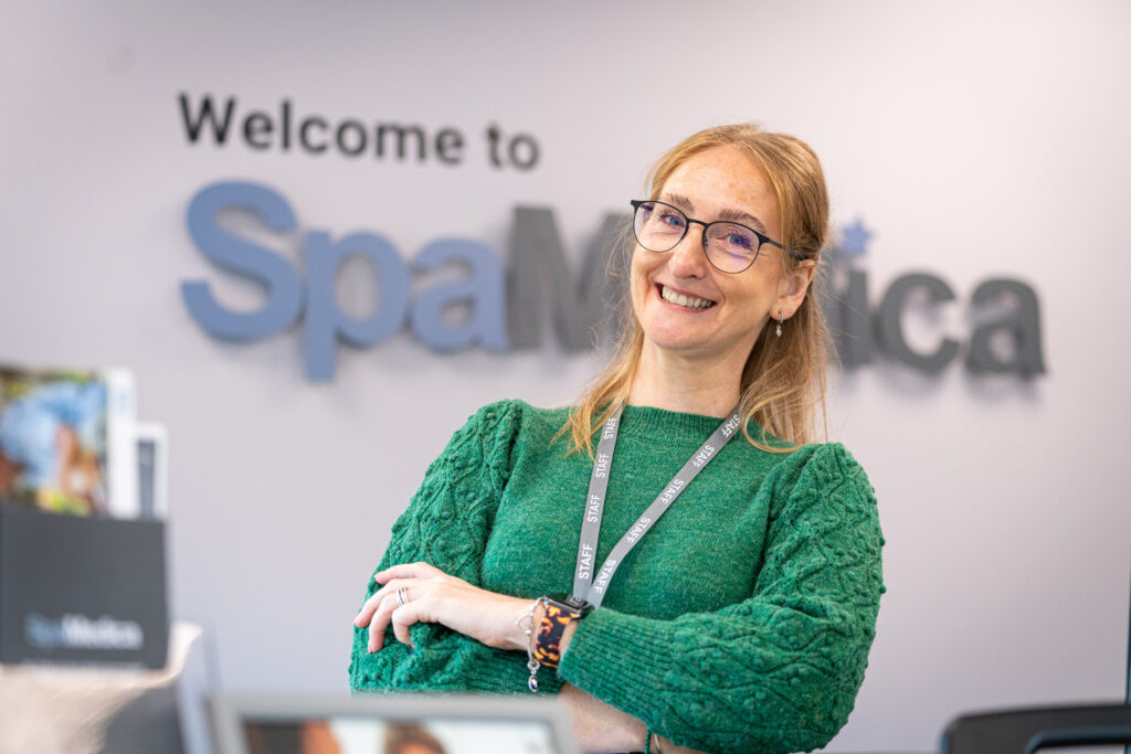 Happy SpaMedica employee stood in reception area with arms crossed