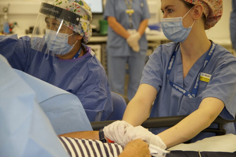 SpaMedica nurse with scrubs and face mask comforting patient during surgery