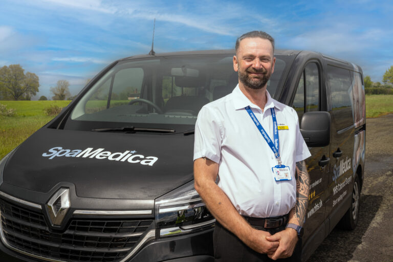 A SpaMedica patient transport bus with a driver, Dave Martin, standing in front