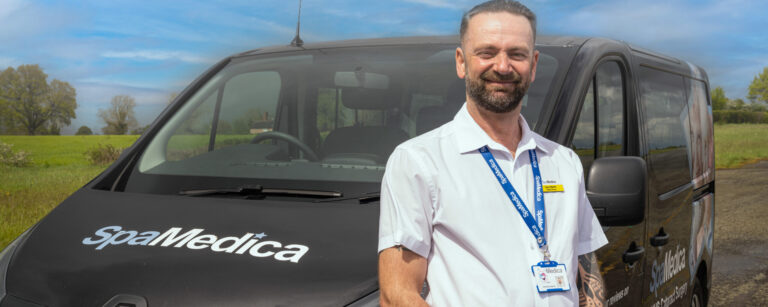 Happy Spamedica Patient Driver stood in front of a SpaMedica Patient Transport van