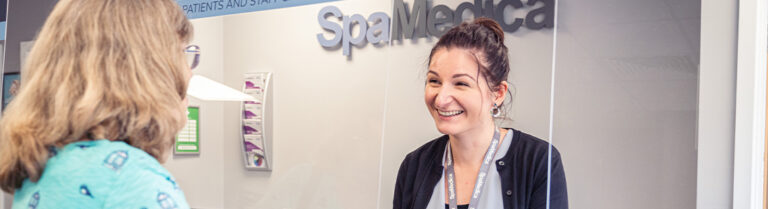 Happy SpaMedica patient coordinator discussing brochure with delighted patient