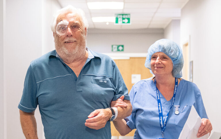 SpaMedica nurse supporting a delighted SpaMedica patient wearing eye shield post surgery