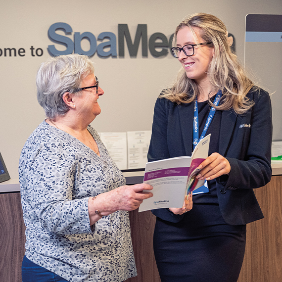 Happy SpaMedica patient coordinator discussing brochure with delighted patient