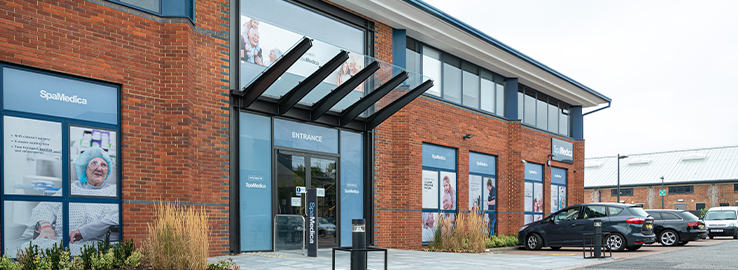 The exterior of the SpaMedica Wokingham hospital displaying images of patients and SpaMedica branding on the windows