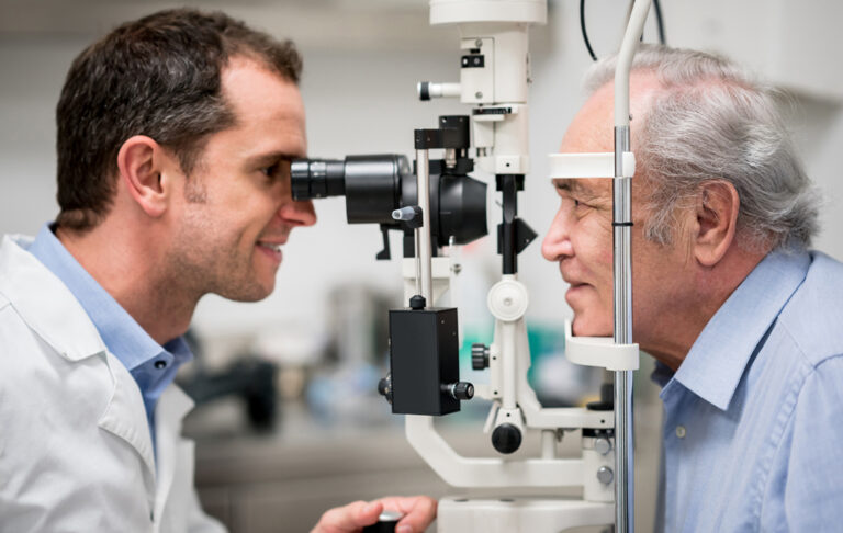 Optometrist using equipment with patient during eye test