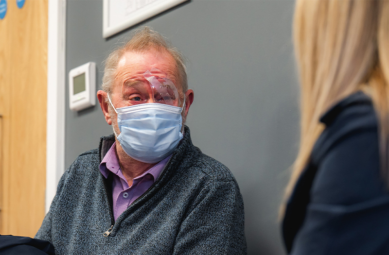 Happy SpaMedica patient with face mask wearing eye mask in reception post surgery