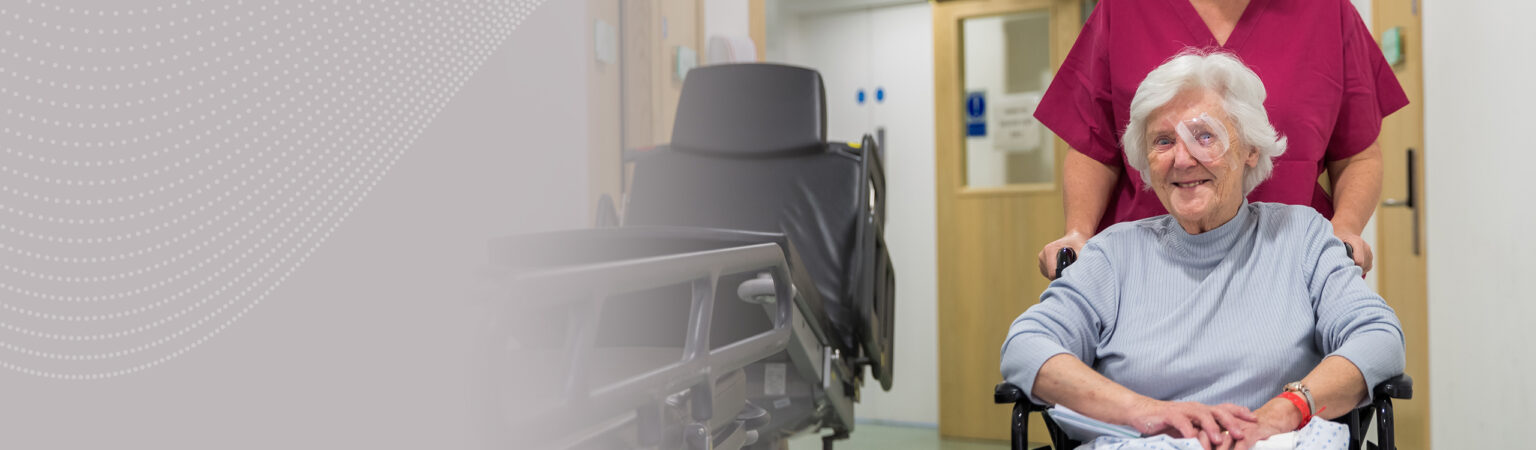 A smiling SpaMedica patient being helped back to the waiting room by a SpaMedica employee after undergoing cataract surgery