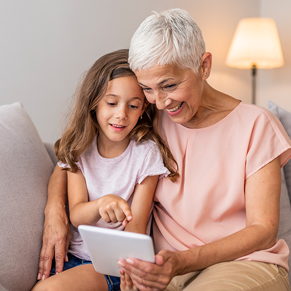 Smiling elderly lady watching a tablet with her granddaughter