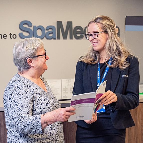 Happy SpaMedica patient coordinator discussing brochure with delighted patient