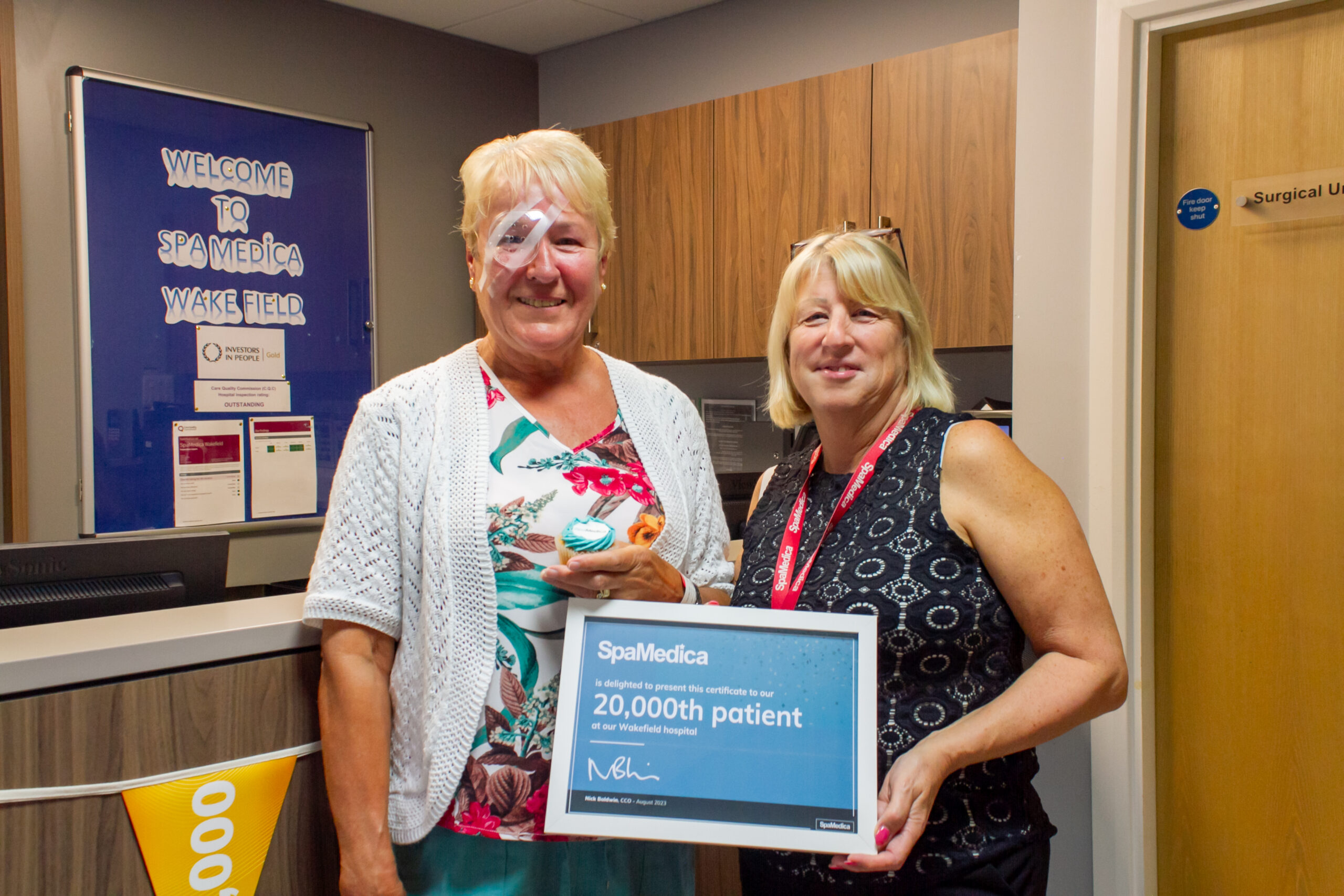 Female patient pictured with hospital manager holding a certificate to celebrate the hospital's 20,000th patient milestone