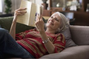Elderly woman reading book on sofa
