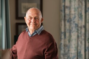 Happy elderly man stood at window