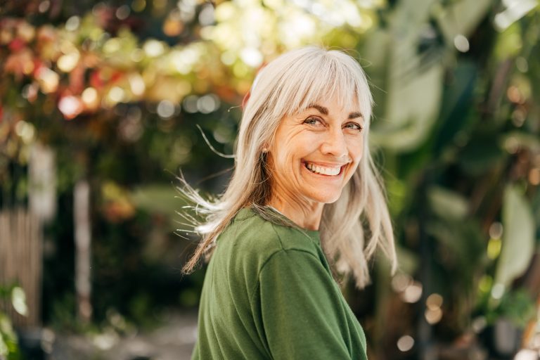 Happy smiling elderly female surrounded by greenery