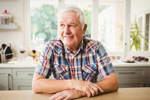 Happy elderly male sat at dining table