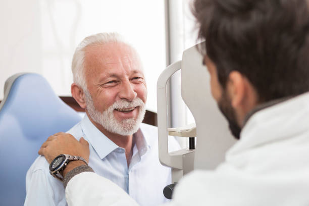 Happy elderly male having eyes examined at the opticians