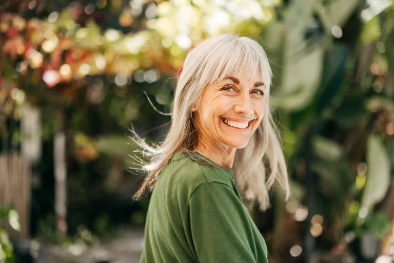 Happy smiling elderly female surrounded by greenery