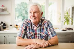 Happy elderly male sat at dining table